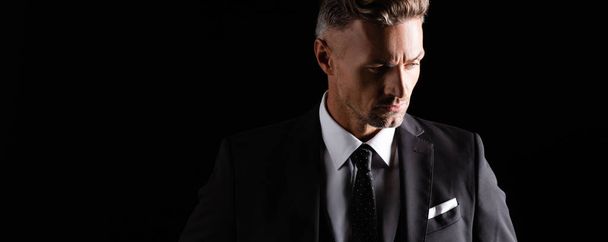Panoramic shot of handsome businessman looking away isolated on black - Фото, зображення
