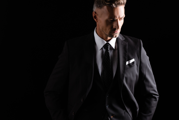 Serious handsome businessman looking away isolated on black - Photo, Image