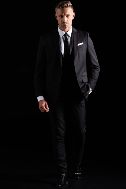 Full length of handsome businessman looking at camera isolated on black  - Фото, зображення