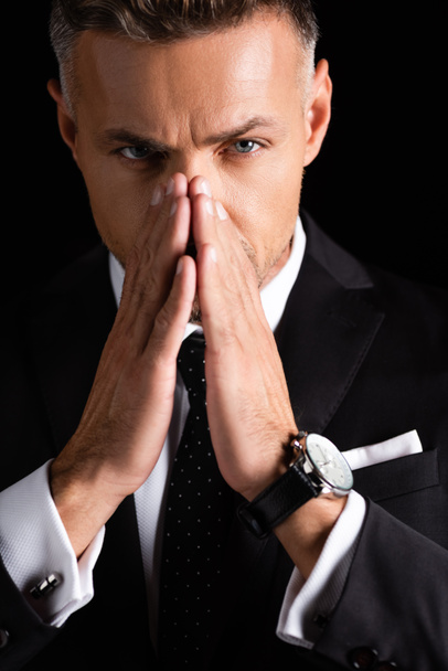 Confident businessman with hands by face looking at camera isolated on black  - Foto, immagini