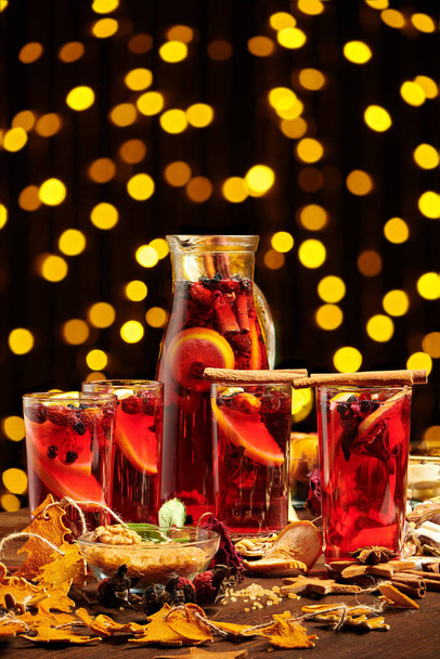 Świąteczne grzane wino lub gluhwein z przyprawami, czekoladowe słodycze i plasterki pomarańczy na rustykalnym stole, tradycyjny napój na zimowe wakacje, świąteczne lampki i dekoracje - Zdjęcie, obraz