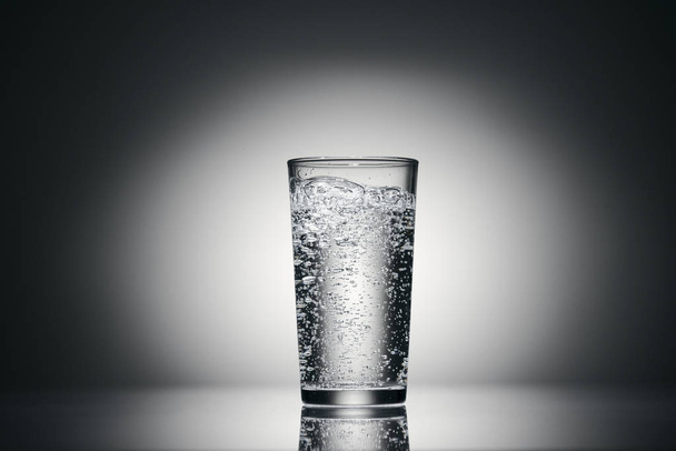 ένα ποτήρι ανθρακούχο νερό σε σκούρο φόντο - Φωτογραφία, εικόνα