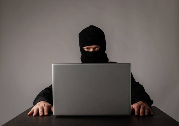 Хакер в маске с помощью ноутбука
. - Фото, изображение