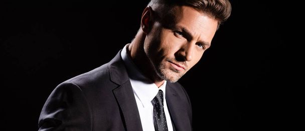 Panoramic shot of handsome businessman looking at camera isolated on black  - Foto, Imagem