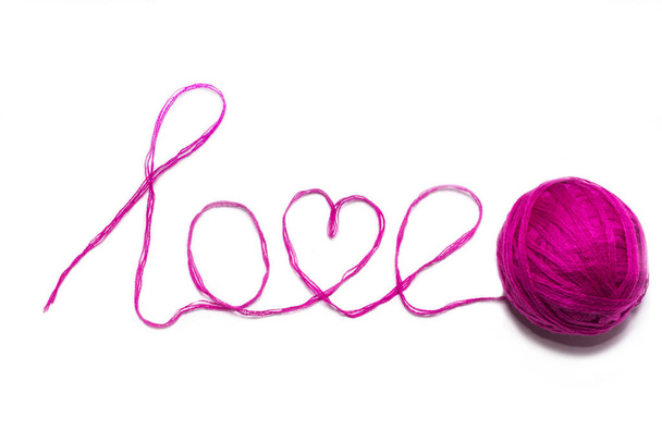 愛という言葉はピンクの糸と白い背景の長方形でできています - 写真・画像