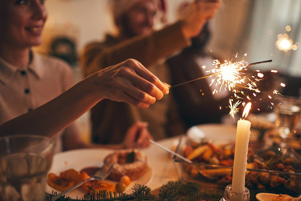 Close up of hand holding sparkler over Christmas dinner background, copy space - Fotografie, Obrázek