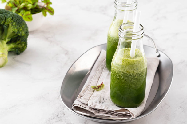 Blended green smoothie with ingredients on the white table. - Photo, Image