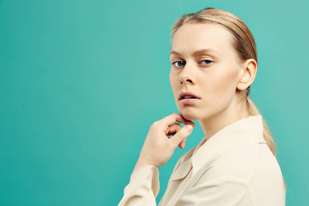 Waist up portrait of blonde businesswoman looking at camera over shoulder while posing against mint blue background, copy space - Фото, зображення