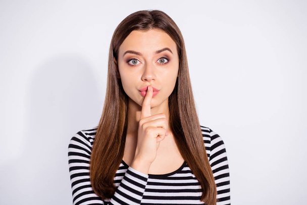 Portrait of minded girl looking with her index finger near face wearing striped pullover isolated over white background - Valokuva, kuva