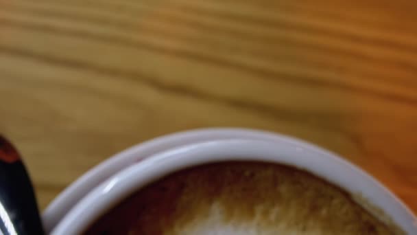 Šálek Cappuccino s bílou pěnou na dřevěném stole v restauraci. Detailní záběr - Záběry, video
