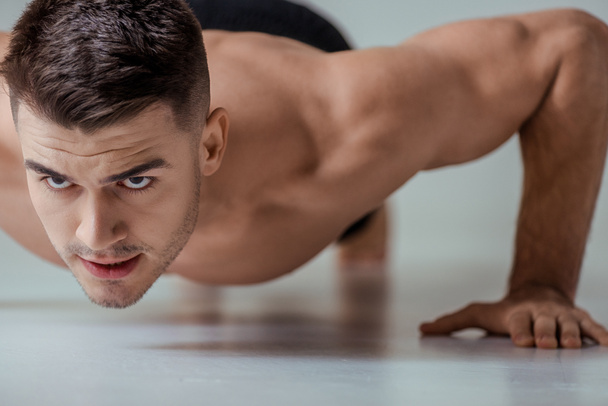 sexy muscular bodybuilder with bare torso doing push ups - Foto, Bild