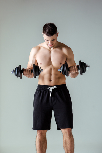 musclé bodybuilder sexy avec torse nu exercice avec haltères isolé sur gris
 - Photo, image