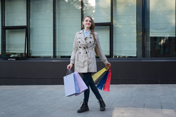 Mujer joven feliz con bolsas de colores cerca del centro comercial. Shopaholic
 - Foto, Imagen