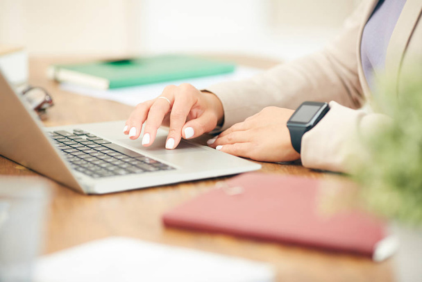 Побочный просмотр крупным планом неузнаваемой бизнес-леди с помощью ноутбука во время работы за столом в офисе, сосредоточиться на женских рук, печатающих на клавиатуре, копировать пространство
 - Фото, изображение