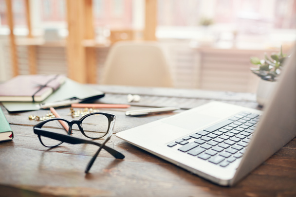 Háttér kép az üzleti iroda laptop és kellékek fa íróasztal, összpontosítson a fekete kemény perem szemüveg előtérben, másolja a helyet - Fotó, kép