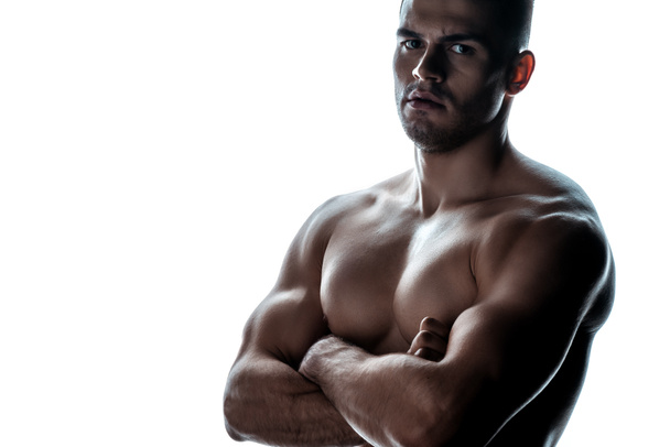 sexy muskulöser Bodybuilder mit nacktem Oberkörper posiert mit verschränkten Armen im Schatten isoliert auf Weiß - Foto, Bild