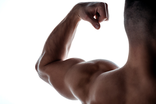 vue recadrée du bodybuilder musculaire montrant des triceps dans l'ombre isolés sur blanc
 - Photo, image