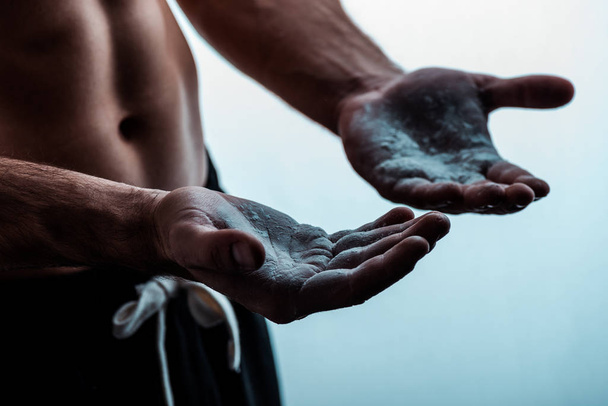καλλιεργημένη άποψη του σέξι μυϊκή bodybuilder με γυμνό κορμό εφαρμογή ταλκ σε σκόνη στα χέρια σε λευκό - Φωτογραφία, εικόνα