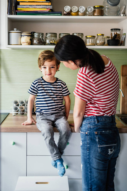 Piccolo ragazzo e sua madre nella loro cucina - Foto, immagini