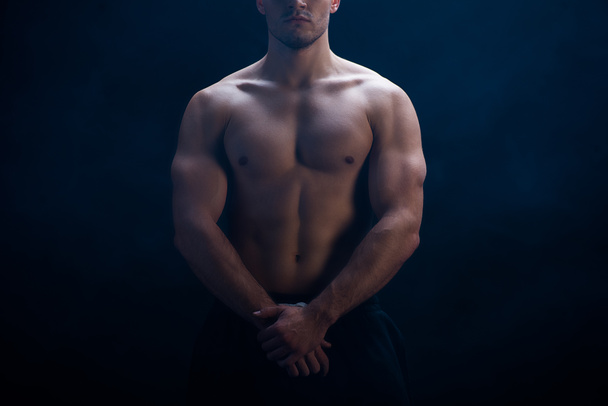 cropped view of sexy muscular bodybuilder with bare torso posing on black background - Foto, Imagen