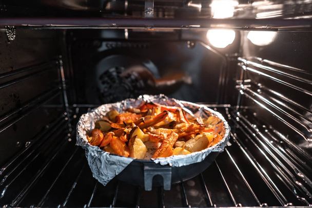 Patatas al horno con zanahoria y otras especias en asador. - Foto, Imagen