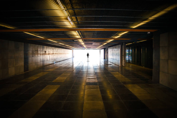 Silhouette de personne méconnaissable et lumière du jour devant dans le tunnel du métro - Photo, image