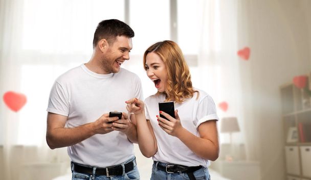 happy couple in white t-shirts with smartphones - Fotoğraf, Görsel
