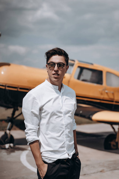 A man standing on the background of a small single engine plane. - 写真・画像