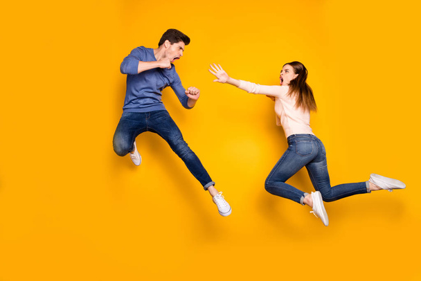 Full body photo of two ninja woman man have fight battle jump kick legs hands feel crazy wear pink blue sweater denim jeans sneakers isolated over yellow color background - Foto, Imagem