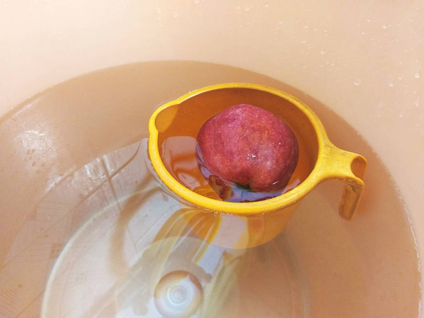 A single red apple placed in a water bucket. - Photo, Image