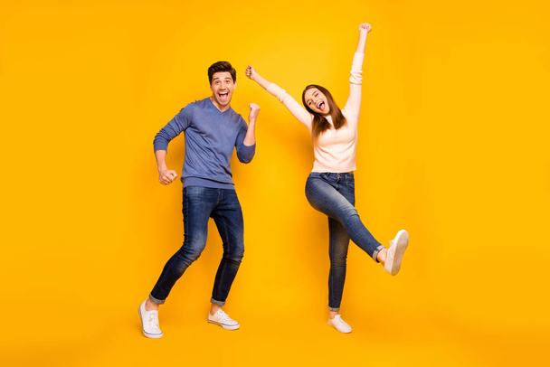 Full body photo of excited funny couple relax rest feel content raise hands wear trendy modern outfit sneakers isolated over vibrant color background - Zdjęcie, obraz