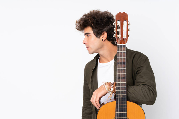 Young caucasian man with guitar over isolated white background - Photo, Image