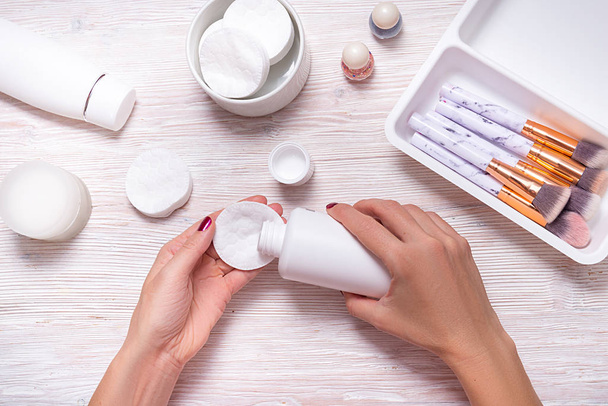 Woman hands holding face lotion and cotton disk - 写真・画像
