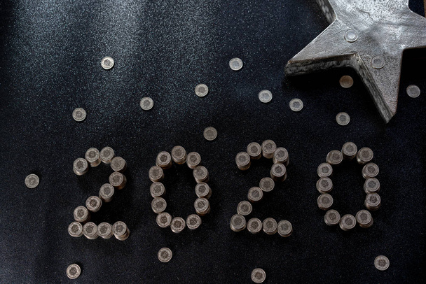 Gráfico de Año Nuevo 2020 hecho de monedas de Suiza en un suelo negro brillante con estrella de plata para concepto
. - Foto, imagen