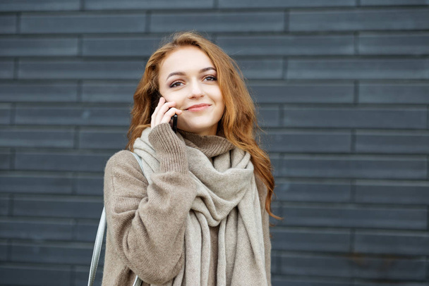 Молода жінка розмовляє по телефону і посміхається на вулиці. Концепція спілкування, роботи, способу життя та молоді
. - Фото, зображення