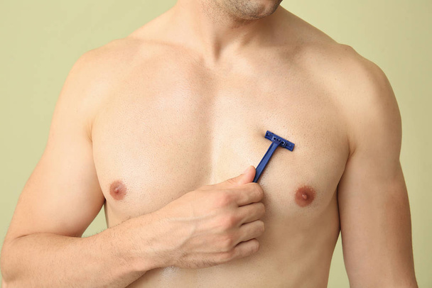 Handsome young man shaving his body on color background, closeup - Photo, Image