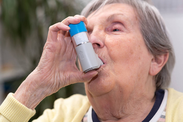 Vieille femme utilisant un inhalateur d'asthme
 - Photo, image