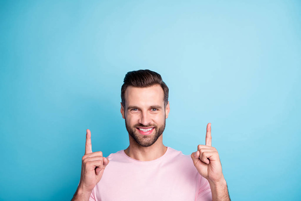 Closeup photo of amazing guy indicating fingers up empty space advising new cool low discount prices best quality products wear casual pink t-shirt isolated blue color background - Foto, imagen