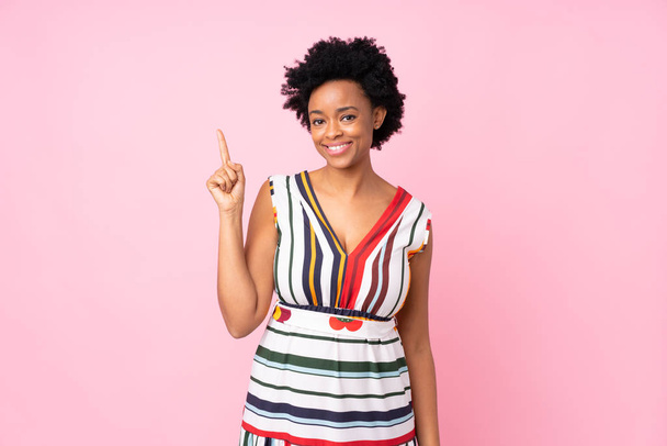 Femme afro-américaine sur fond rose isolé montrant et levant un doigt en signe du meilleur
 - Photo, image
