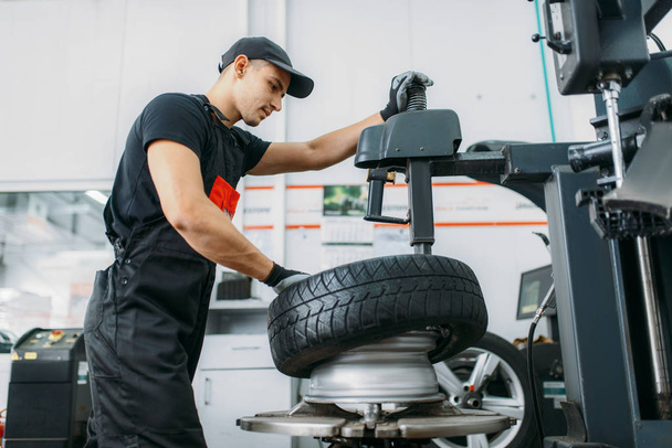 Neumático de cambio mecánico, servicio de reparación. El hombre repara el neumático del coche en el garaje, inspección profesional del automóvil en taller
 - Foto, Imagen
