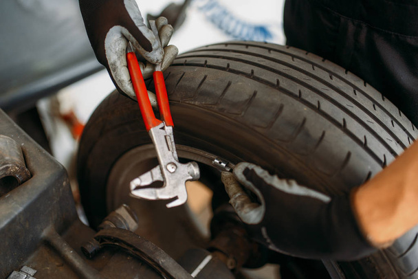 Автомеханическое балансирующее колесо на специальной машине, обслуживание шин. Человек ремонтирует автомобильные шины в гараже, профессиональный автомобильный осмотр в мастерской
 - Фото, изображение