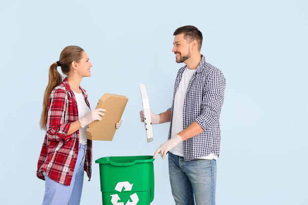 色の背景にゴミのための容器付きのカップル。リサイクルの概念 - 写真・画像