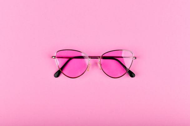 Pink glasses on a pink background. Glamor and style. Glasses for women. The apartment was lying. A place to write. Advertising studio shot of pink glasses. - Photo, Image