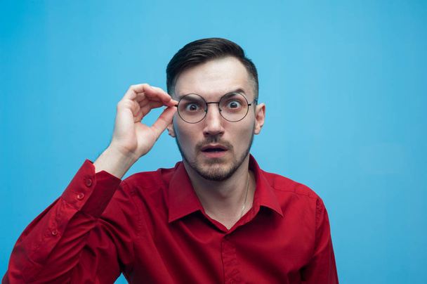 Shocked young man in glasses and a burgundy shirt - Фото, изображение