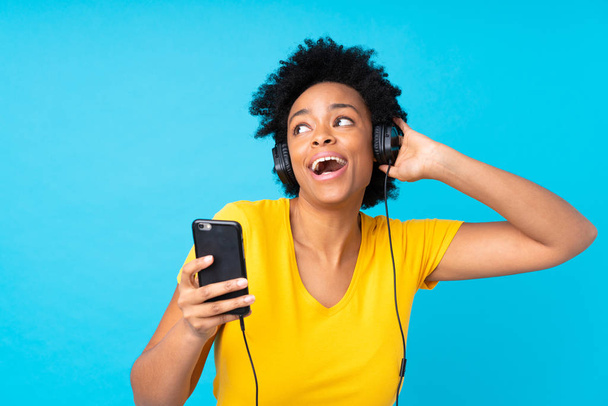 Joven afroamericana mujer escuchando música con un móvil sobre
  - Foto, imagen