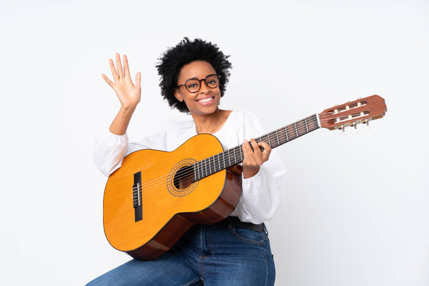 Africano americano mulher com guitarra sobre fundo isolado saudando com a mão com expressão feliz
 - Foto, Imagem