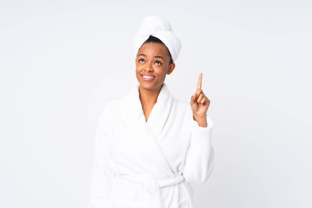 afrikanisch-amerikanische Frau im Bademantel über isoliertem Hintergrund zeigt mit dem Zeigefinger auf eine großartige Idee - Foto, Bild
