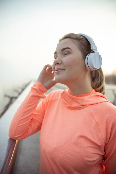 Cute lady in headphones listening to music outdoors - Fotó, kép