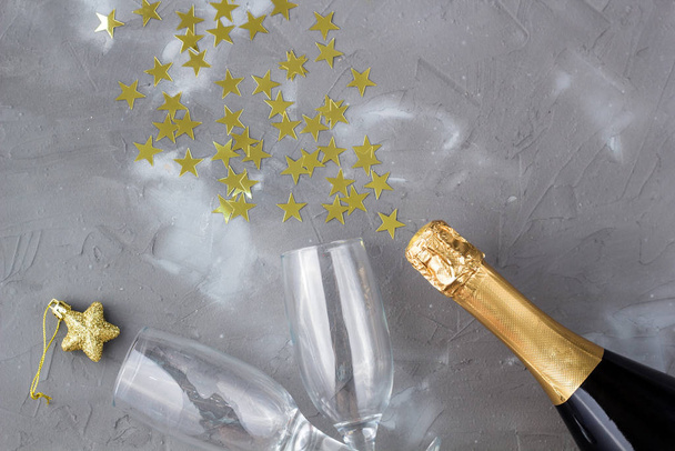 Şampanya şişesi ve altın konfeti yıldızlı bardaklar. Noel, doğum günü ya da düğün kavramı - Fotoğraf, Görsel