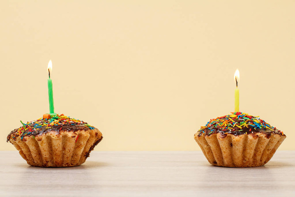 Muffins d'anniversaire avec des bougies festives brûlantes sur fond beige
. - Photo, image